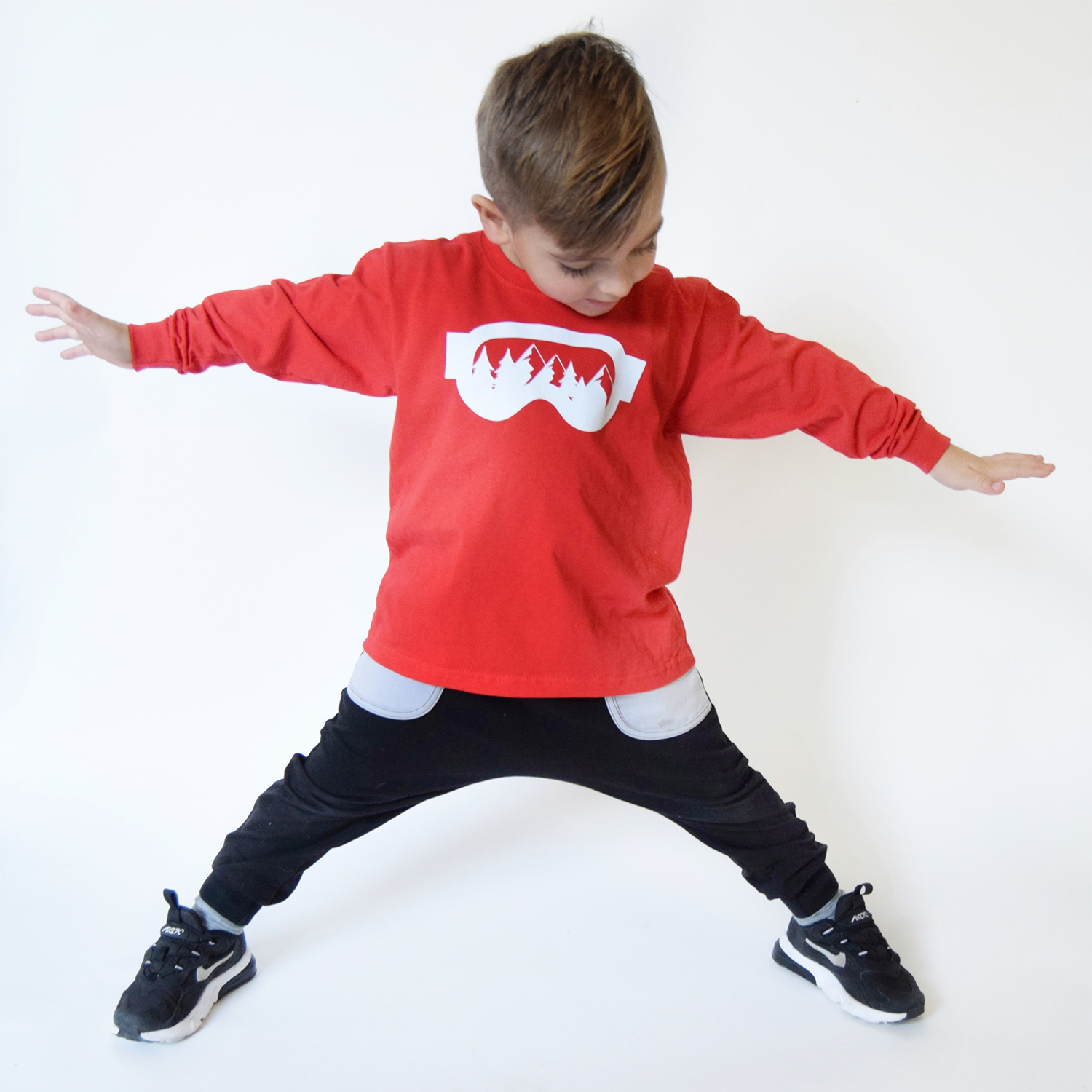 Young boy, wearing red shirt with long sleeves, with ski goggles print by KMLeon.