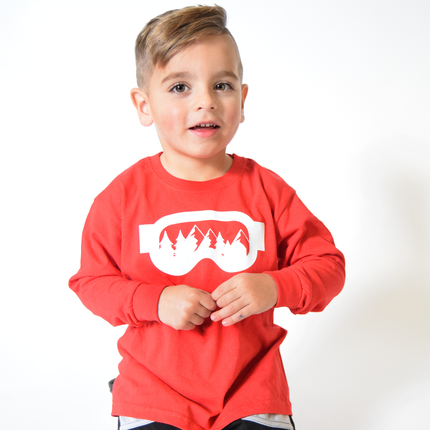 Young boy smiling, wearing red shirt with long sleeves, with ski goggles print by KMLeon.